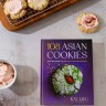 Photo of the book 108 Asian Cookies next to sugar cookies with pink frosting
